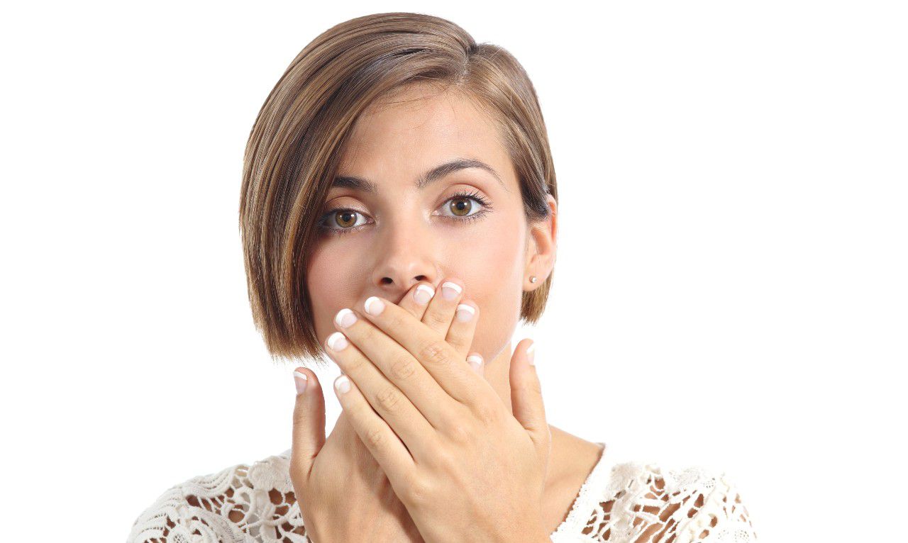 woman hiding her teeth with her hands.